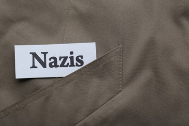 Card with word Nazis on grey jacket, top view