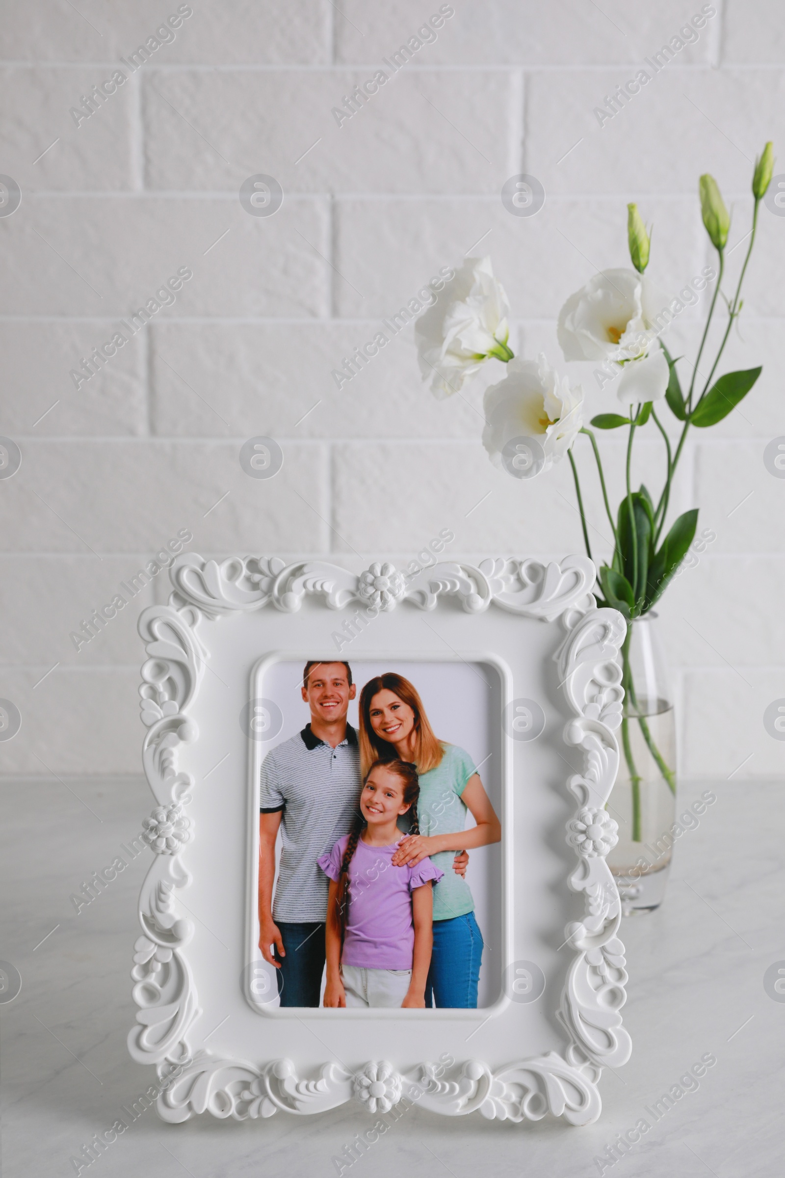 Photo of Framed family photo near beautiful bouquet on white table