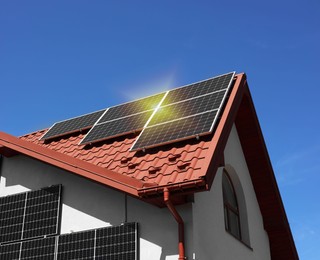 Photo of House with installed solar panels under blue sky. Alternative energy source