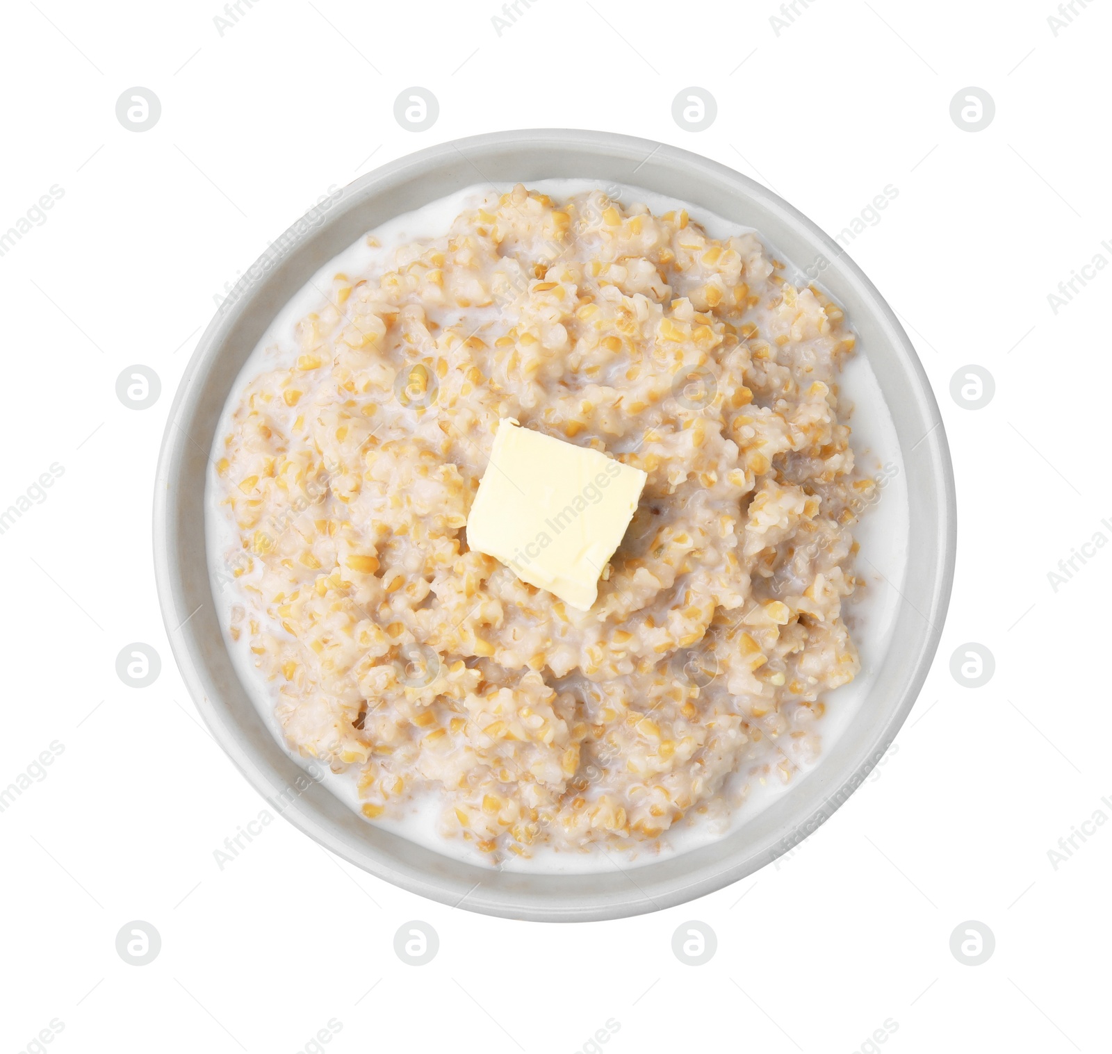 Photo of Tasty wheat porridge with milk and butter in bowl isolated on white, top view