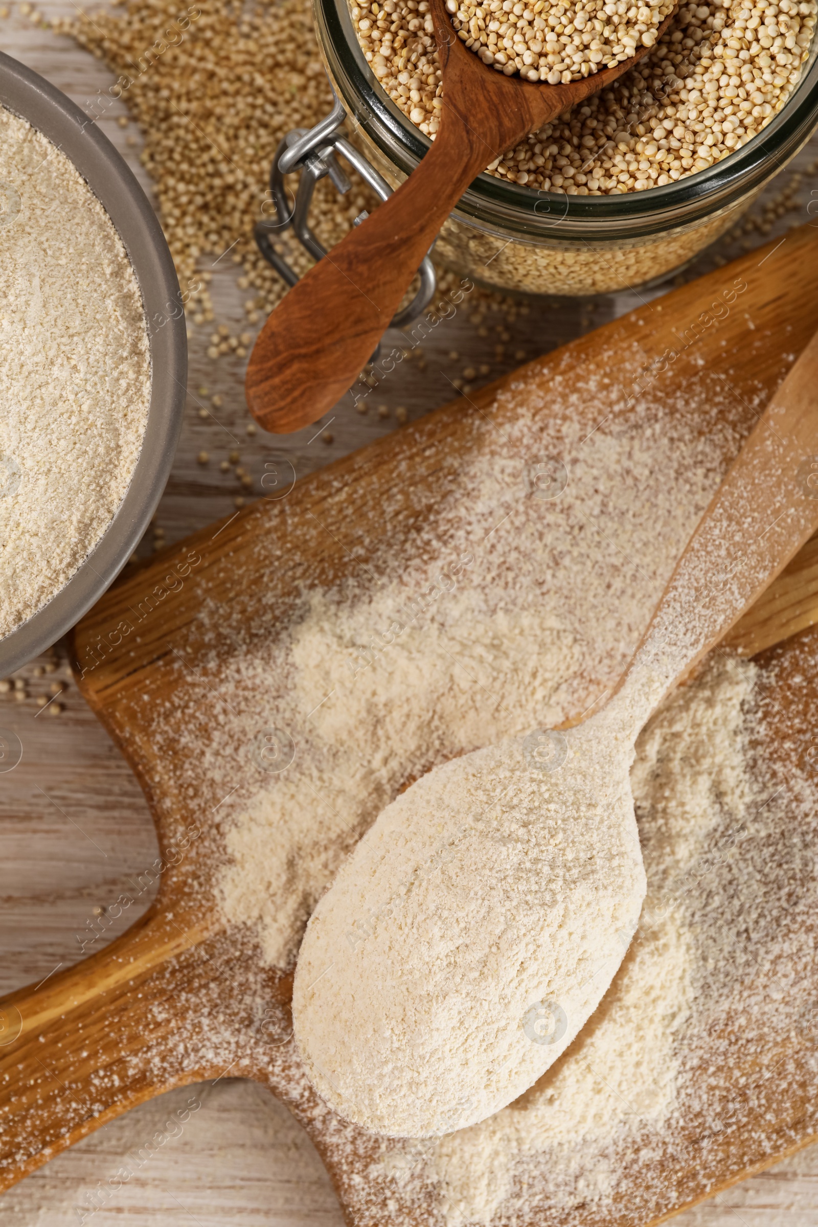 Photo of Spoon and bowl of quinoa flour near jar with seeds on wooden table, flat lay