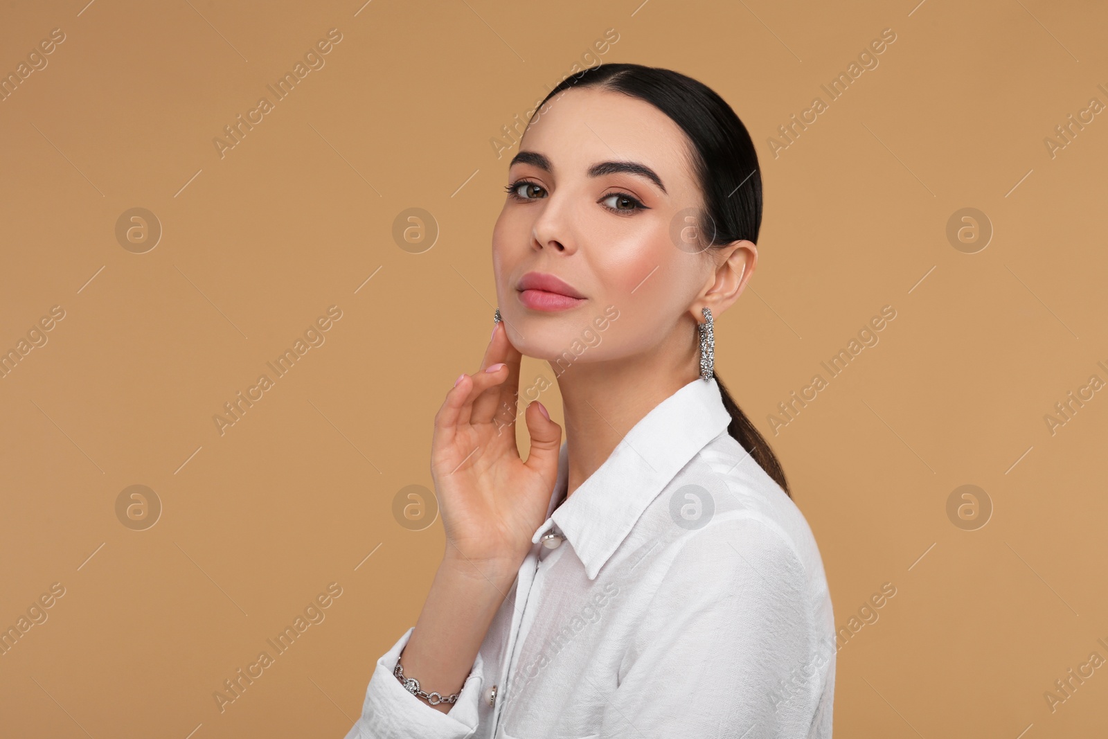 Photo of Beautiful young woman with elegant jewelry on beige background