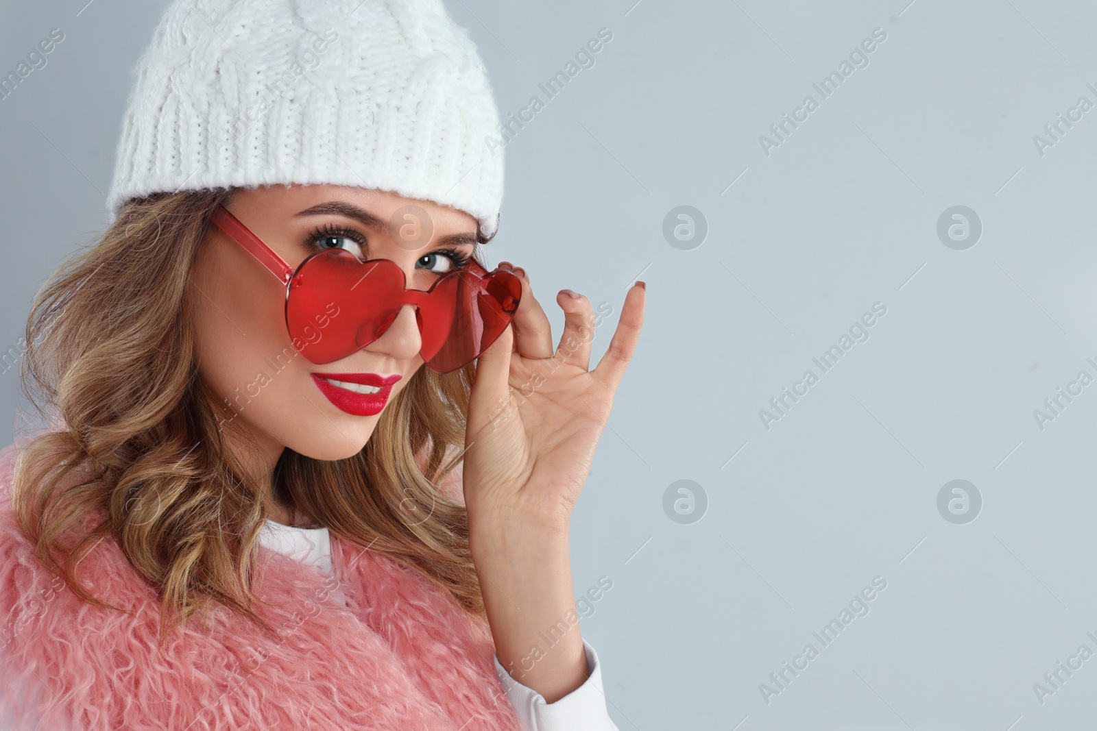 Photo of Young woman wearing heart shaped sunglasses on grey background. Space for text