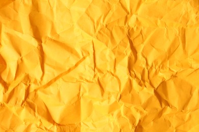 Photo of Texture of orange crumpled paper as background, closeup