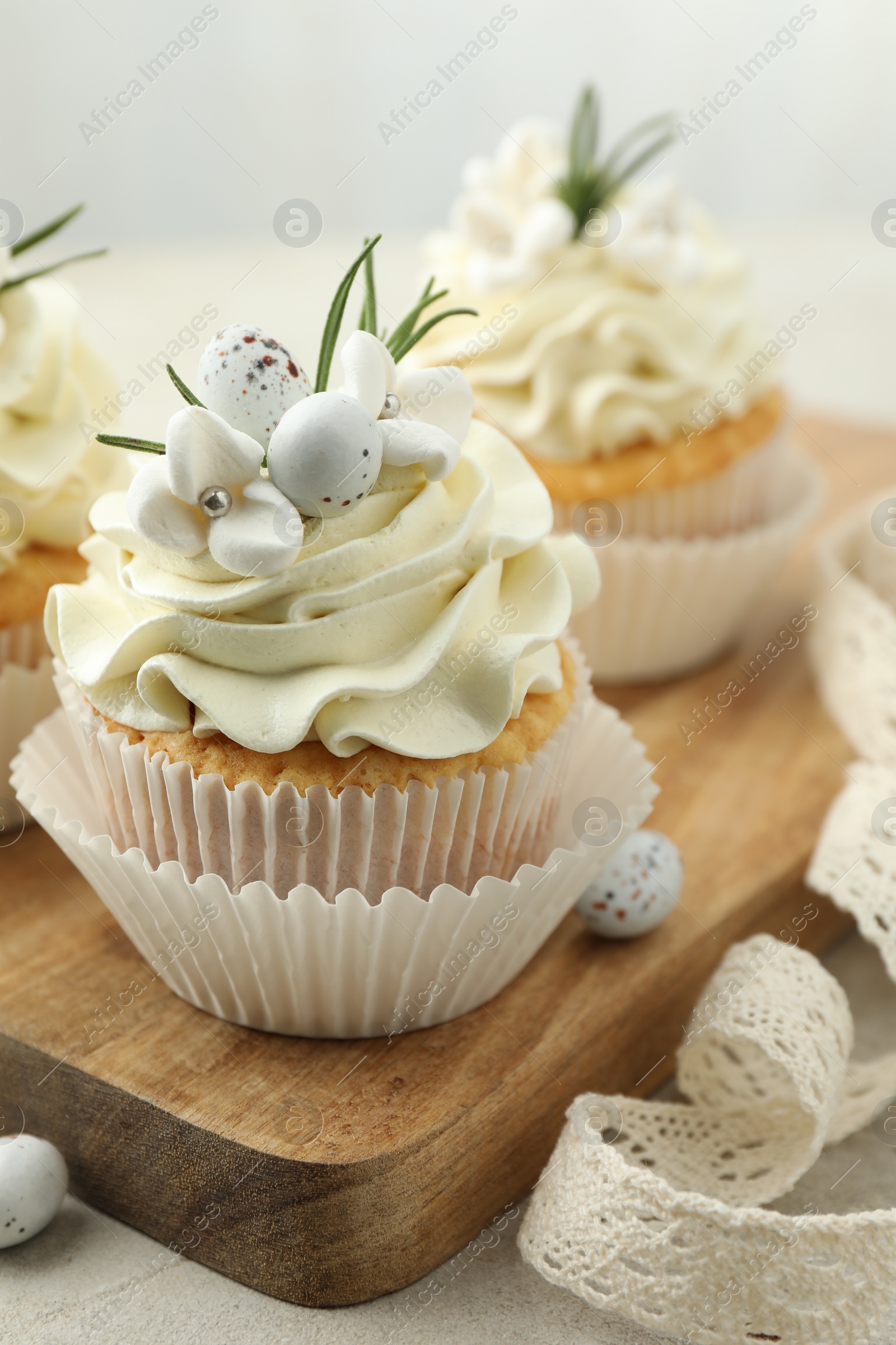 Photo of Tasty Easter cupcakes with vanilla cream and ribbon on gray table, closeup