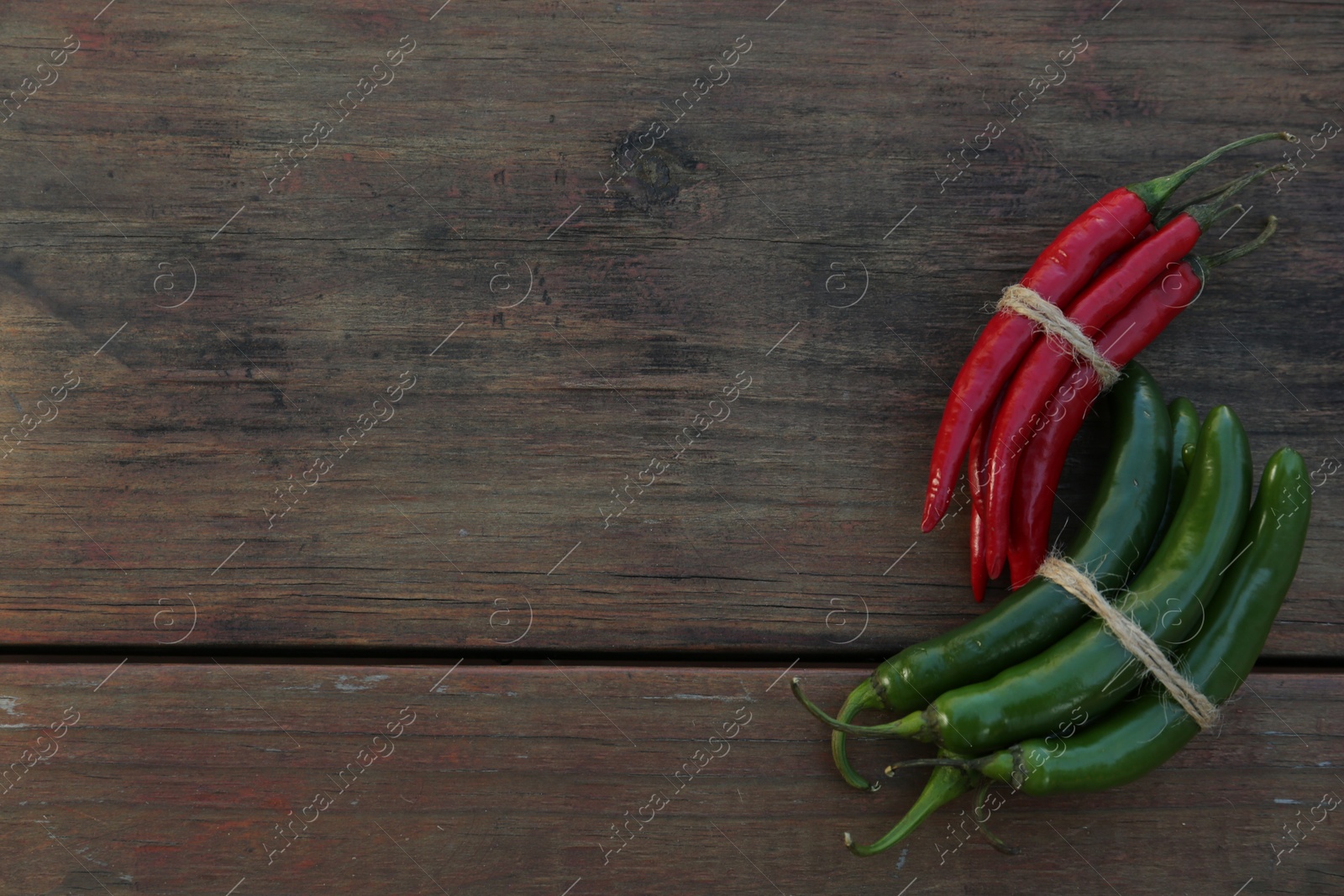 Photo of Different fresh ripe chili peppers on wooden table, flat lay. Space for text