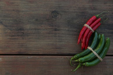Photo of Different fresh ripe chili peppers on wooden table, flat lay. Space for text