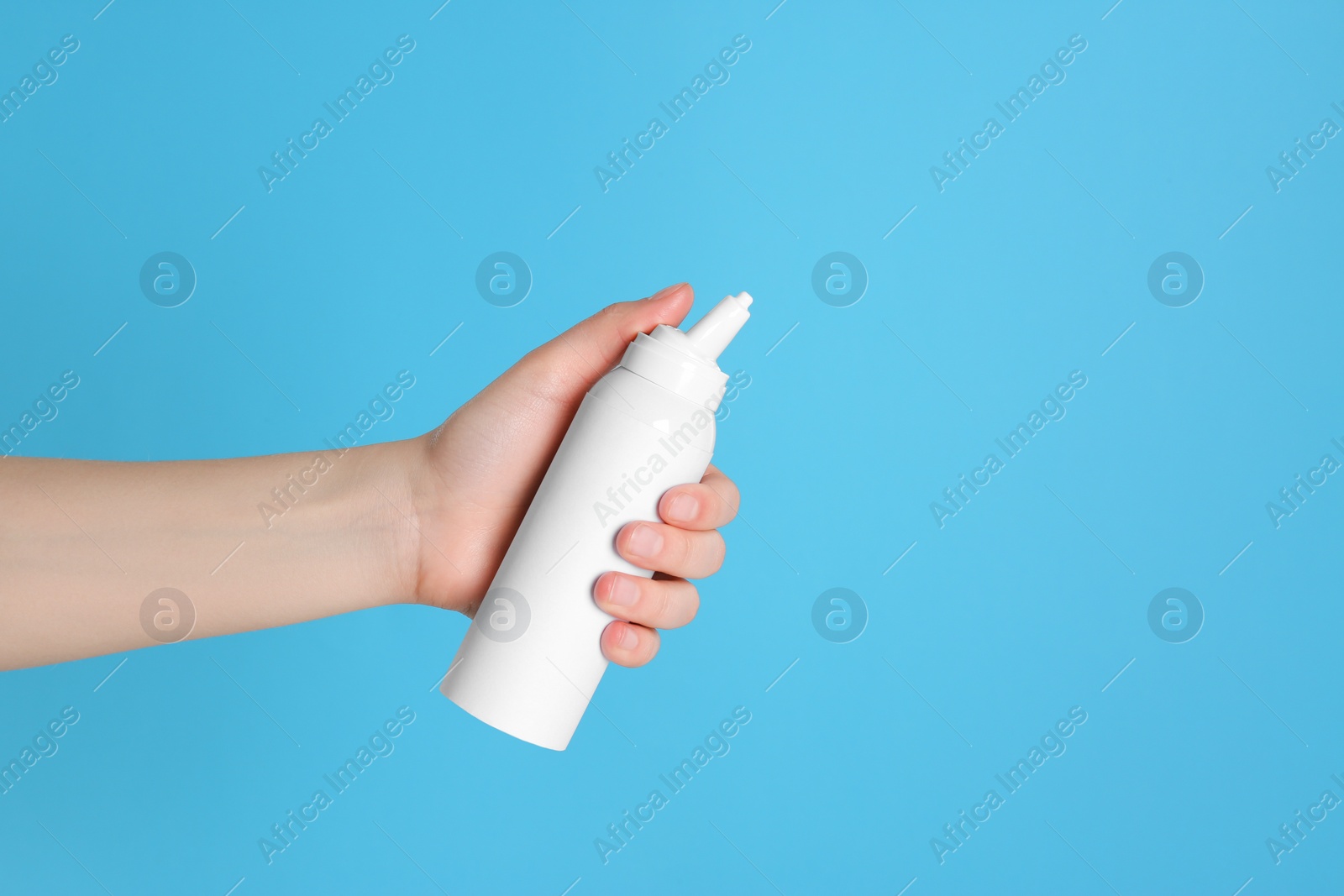 Photo of Woman holding nasal spray on light blue background, closeup