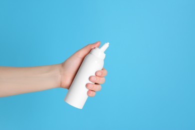 Photo of Woman holding nasal spray on light blue background, closeup