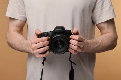 Photo of Photographer holding camera on beige background, closeup