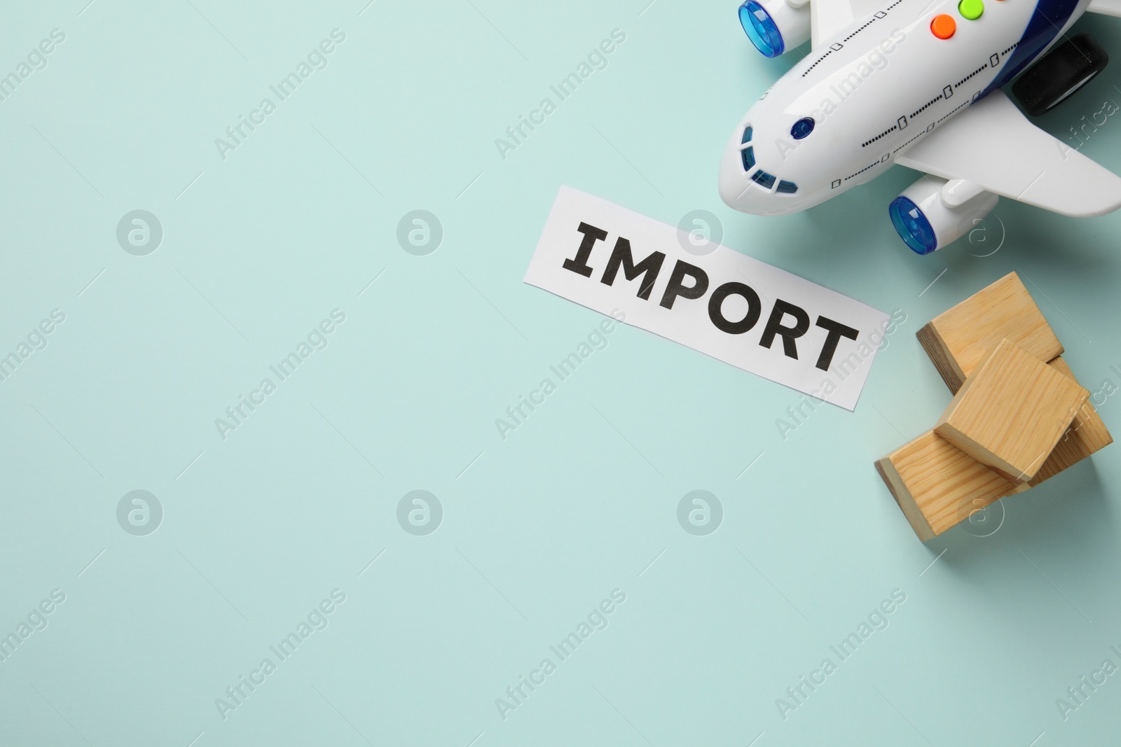 Photo of Import concept. Flat lay composition with toy plane and wooden cubes on light blue background. Space for text