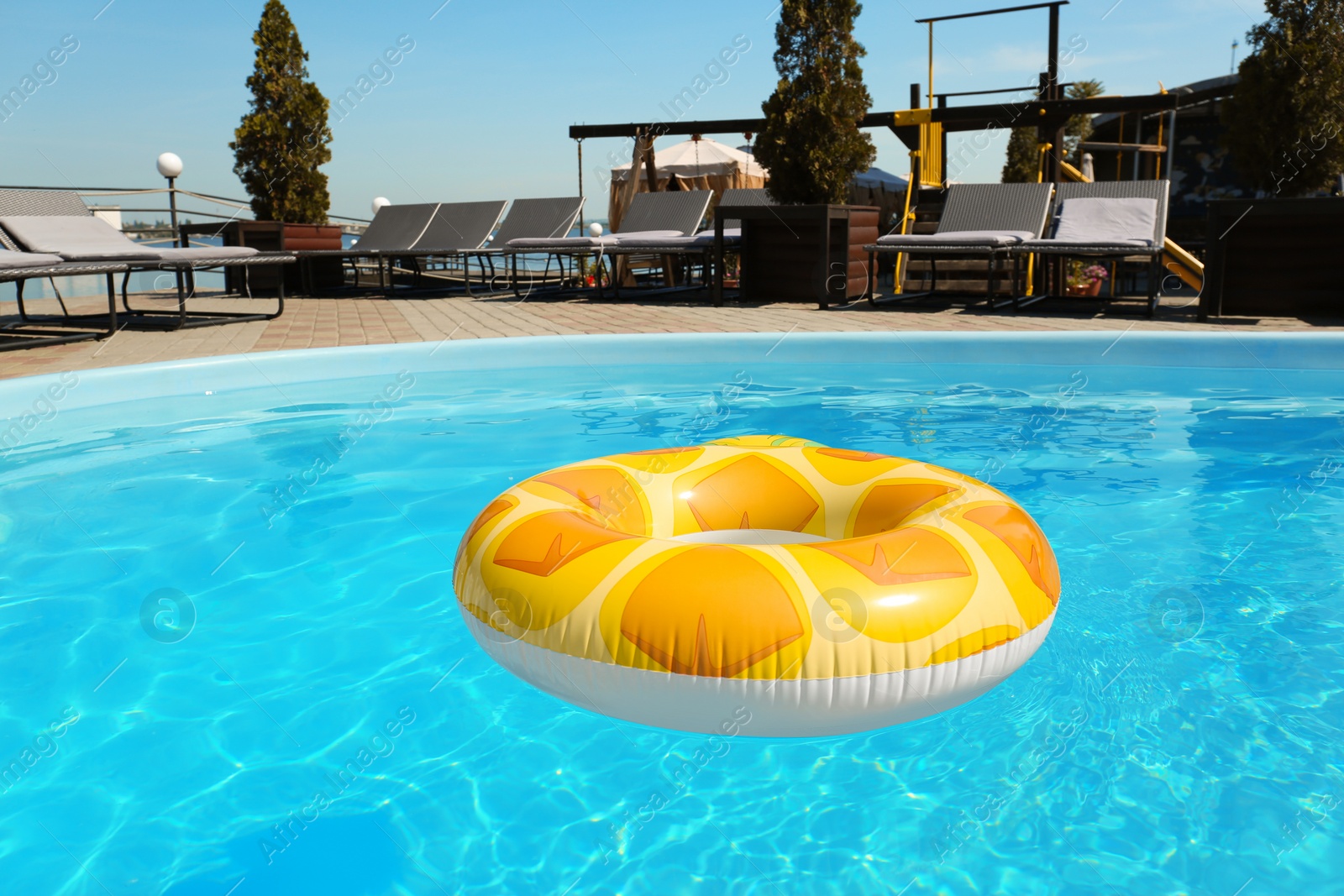 Photo of Colorful inflatable ring floating in swimming pool on sunny day, outdoors