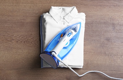 Flat lay composition with folded clothes and iron on wooden table