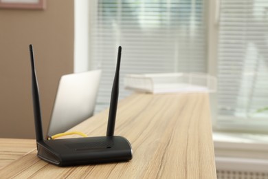 Photo of Modern wi-fi router on wooden counter indoors