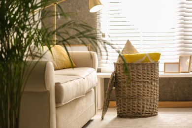 Basket with soft plaid and pillows in living room interior