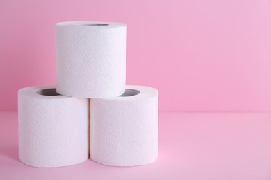 Photo of Soft toilet paper rolls on pink background, closeup. Space for text