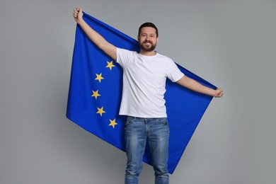 Photo of Man holding European Union flag on light grey background