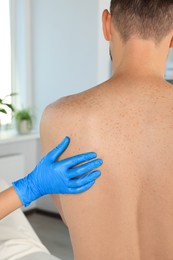 Dermatologist examining patient's birthmark in clinic, closeup