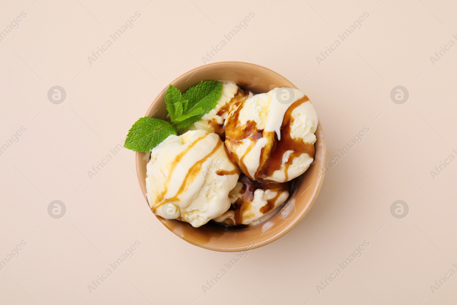 Photo of Scoops of ice cream with caramel sauce and mint leaves on beige table, top view