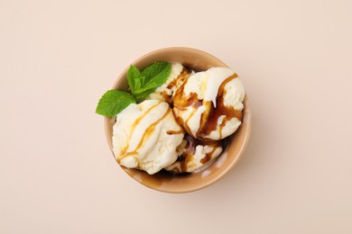 Photo of Scoopsice cream with caramel sauce and mint leaves on beige table, top view