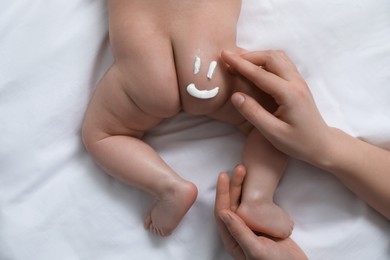 Photo of Mother applying body cream on her little baby, top view