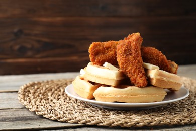 Delicious Belgium waffles served with fried chicken and butter on wooden table, closeup. Space for text