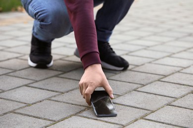 Man taking dropped smartphone from pavement, closeup. Device repairing