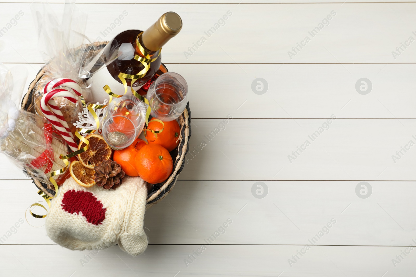 Photo of Wicker basket with Christmas gift set on white wooden table, top view. Space for text