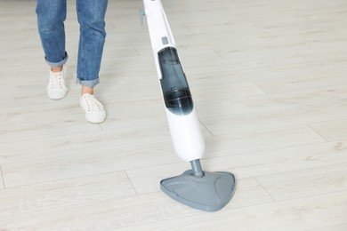 Woman cleaning floor with steam mop at home, closeup