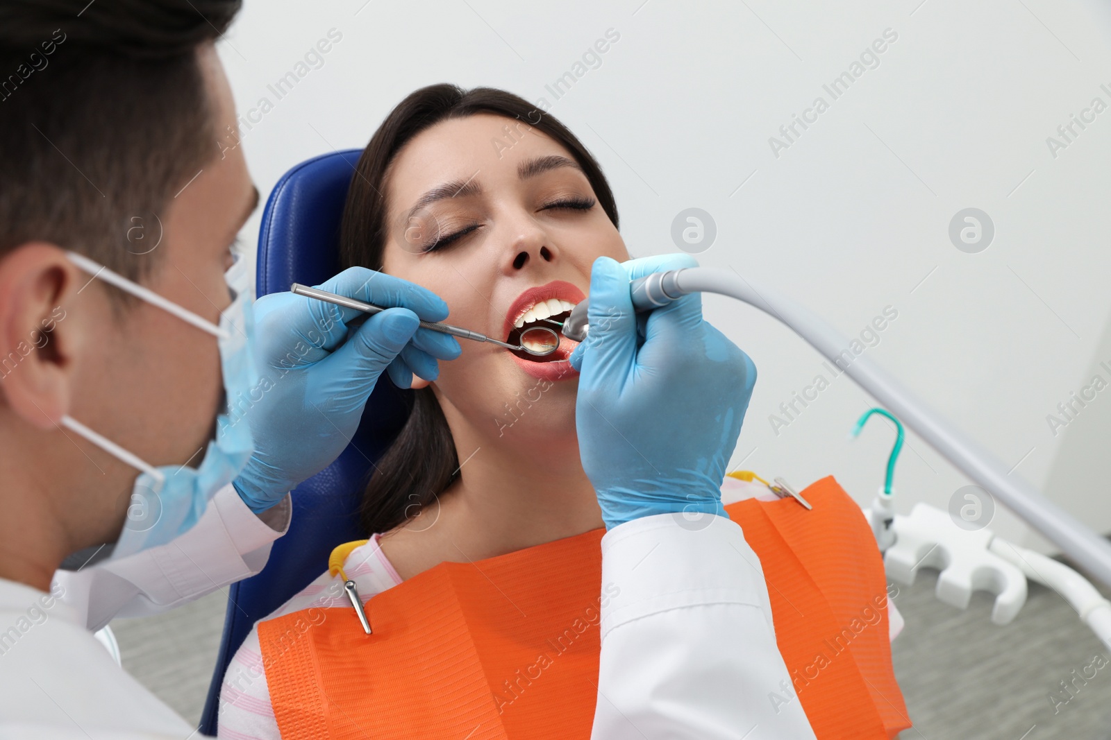 Photo of Professional dentist working with patient in clinic