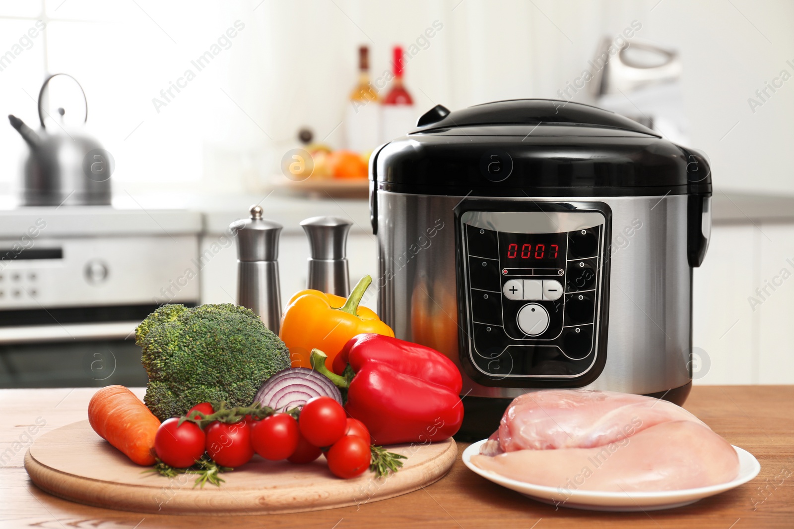 Photo of Modern multi cooker and products on wooden table in kitchen. Space for text