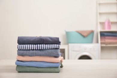 Stack of fresh laundry on white table in bathroom. Space for text