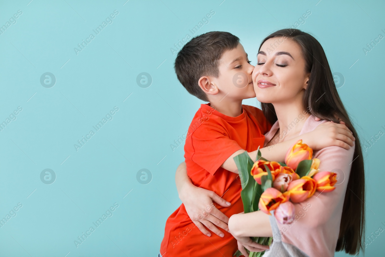 Photo of Portrait of happy woman with flowers and her son on color background. Mother's day celebration