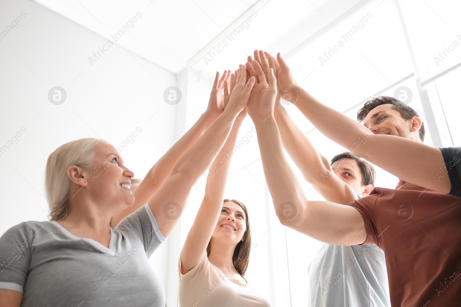 Photo of People putting hands together on light background. Unity concept