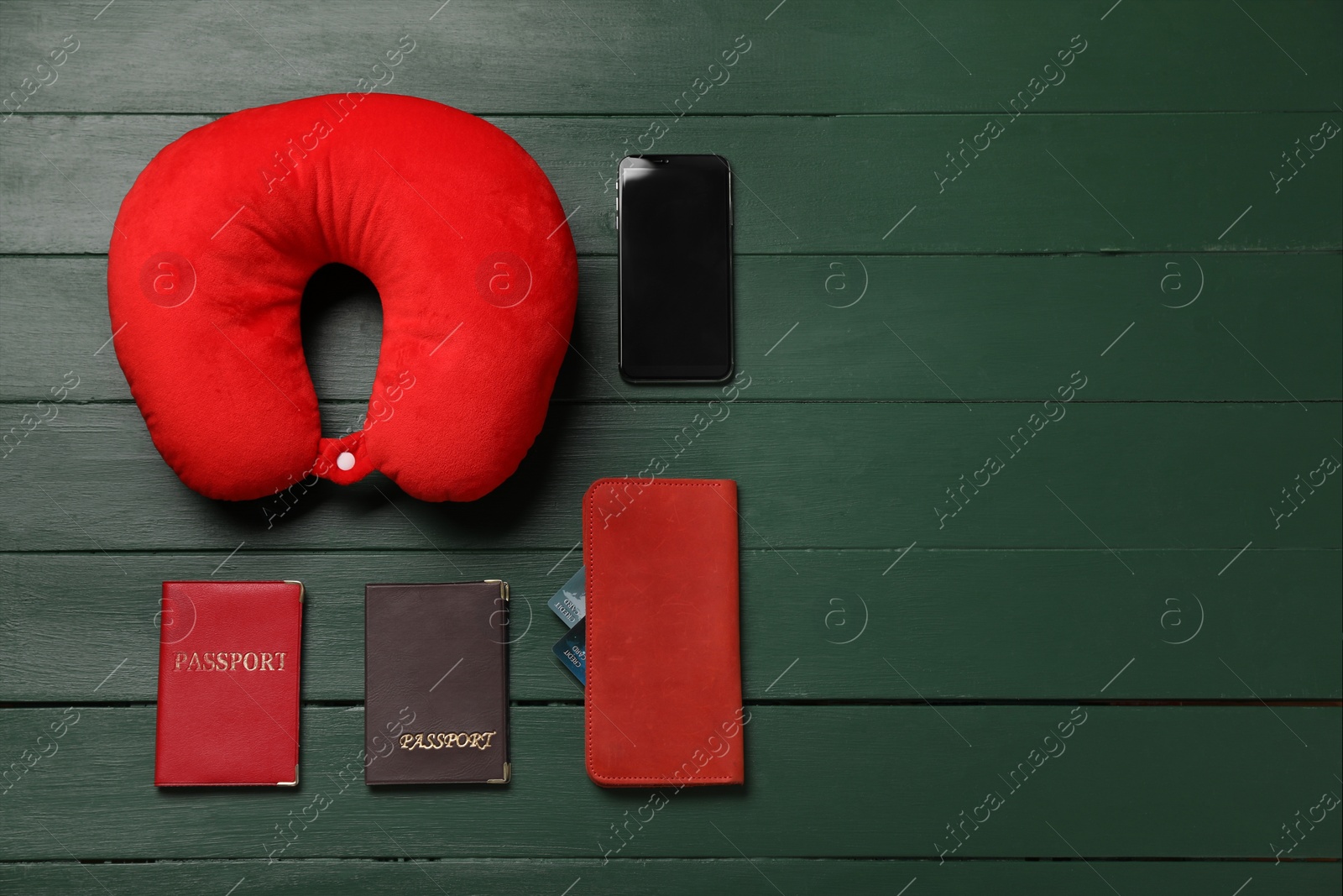 Photo of Flat lay composition with red travel pillow and smartphone on green wooden background, space for text