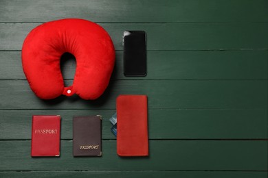 Photo of Flat lay composition with red travel pillow and smartphone on green wooden background, space for text