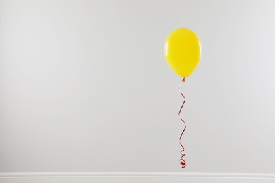 Bright balloon against light wall, space for text. Celebration time