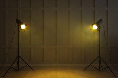Photo of Bright yellow spotlights near wall indoors, space for text