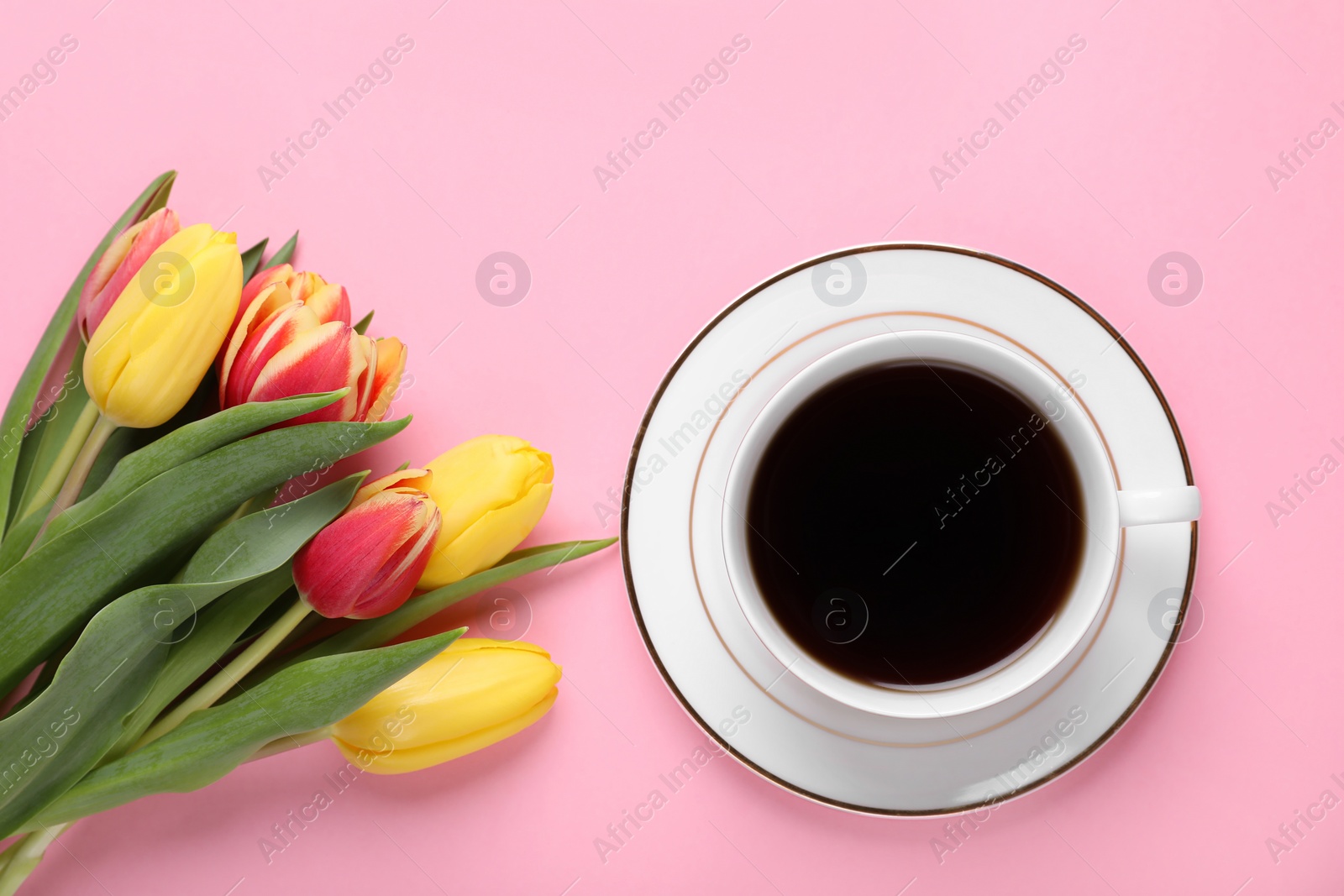 Photo of Cup of coffee and beautiful tulips on pink background, flat lay