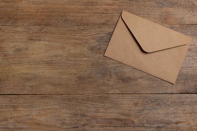 Photo of Paper envelope on wooden table, top view. Space for text