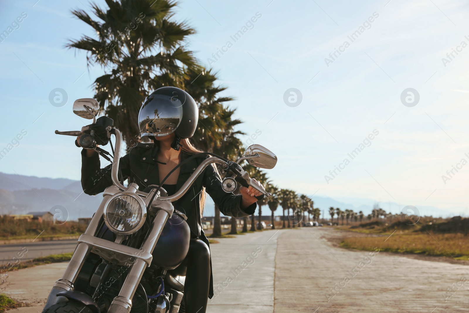 Photo of Woman in helmet riding motorcycle on sunny day