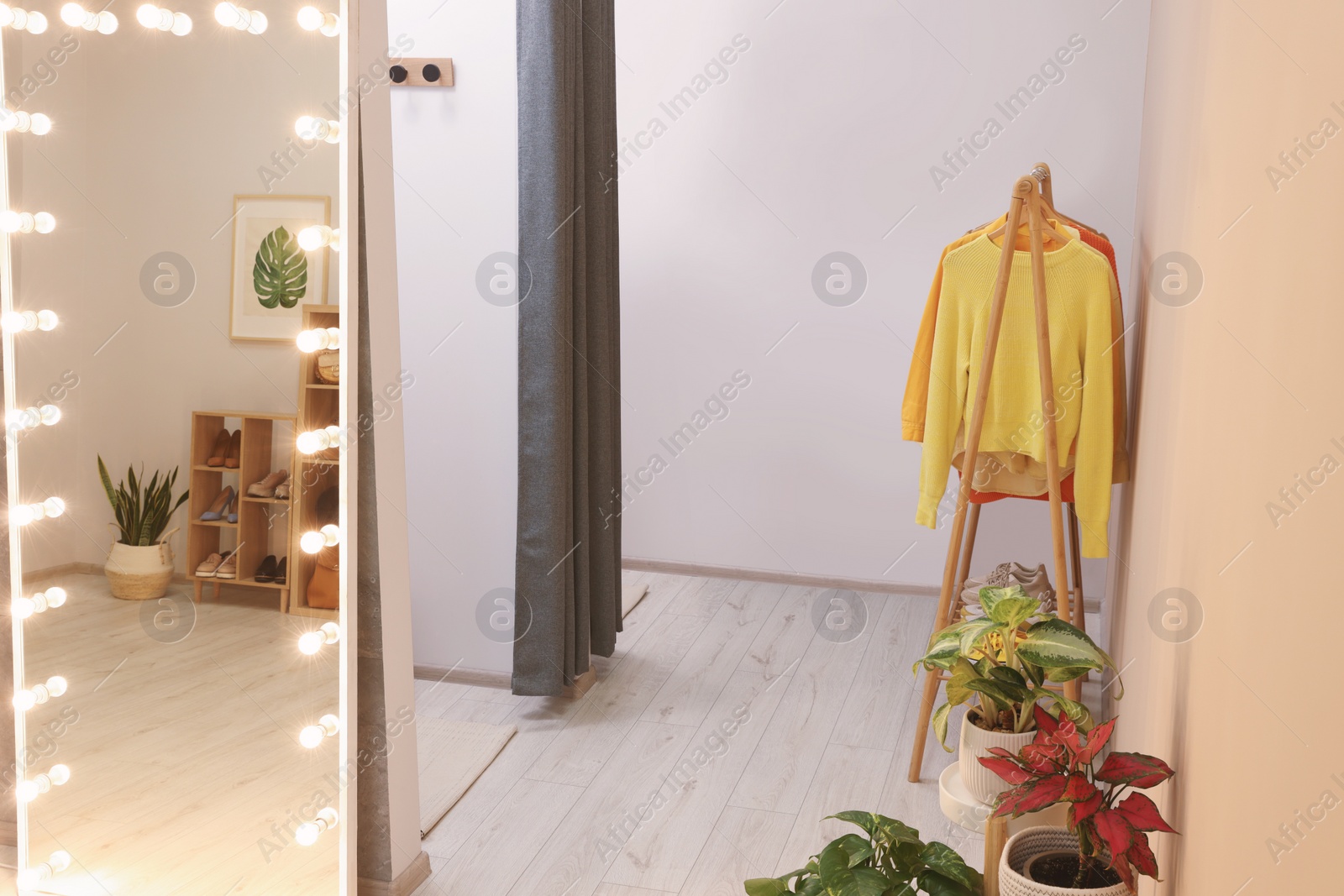 Photo of Stylish dressing room interior with mirror and clothing rack