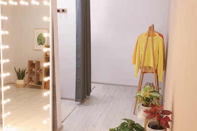 Photo of Stylish dressing room interior with mirror and clothing rack