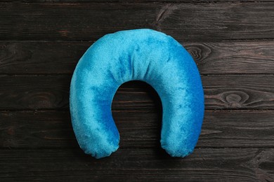 Blue travel pillow on wooden background, top view 