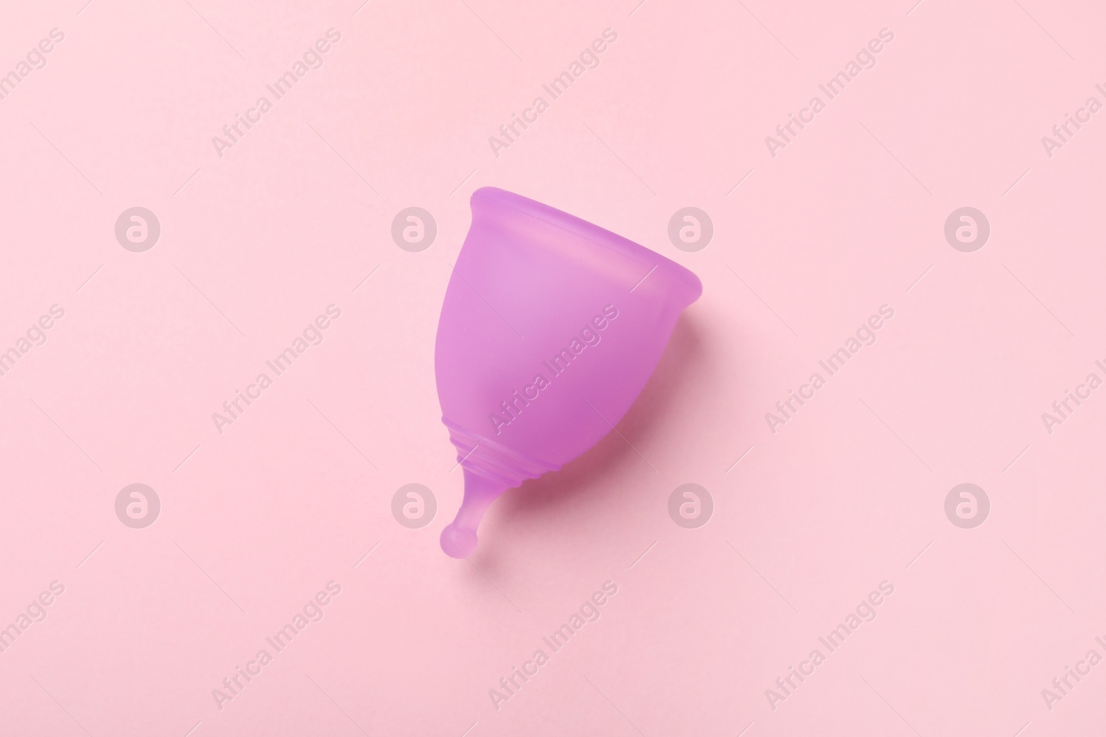 Photo of Violet menstrual cup on pink background, top view