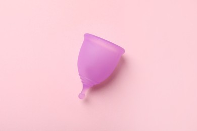 Violet menstrual cup on pink background, top view