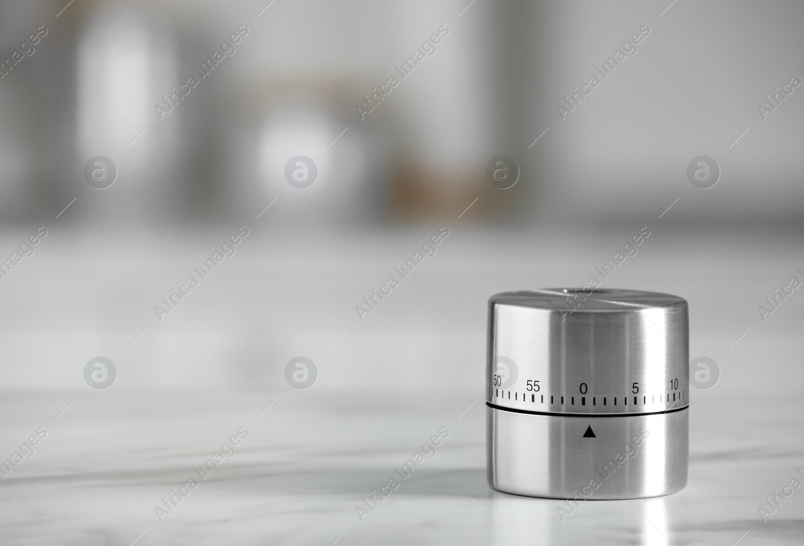 Photo of Kitchen timer on white marble table against blurred background. Space for text