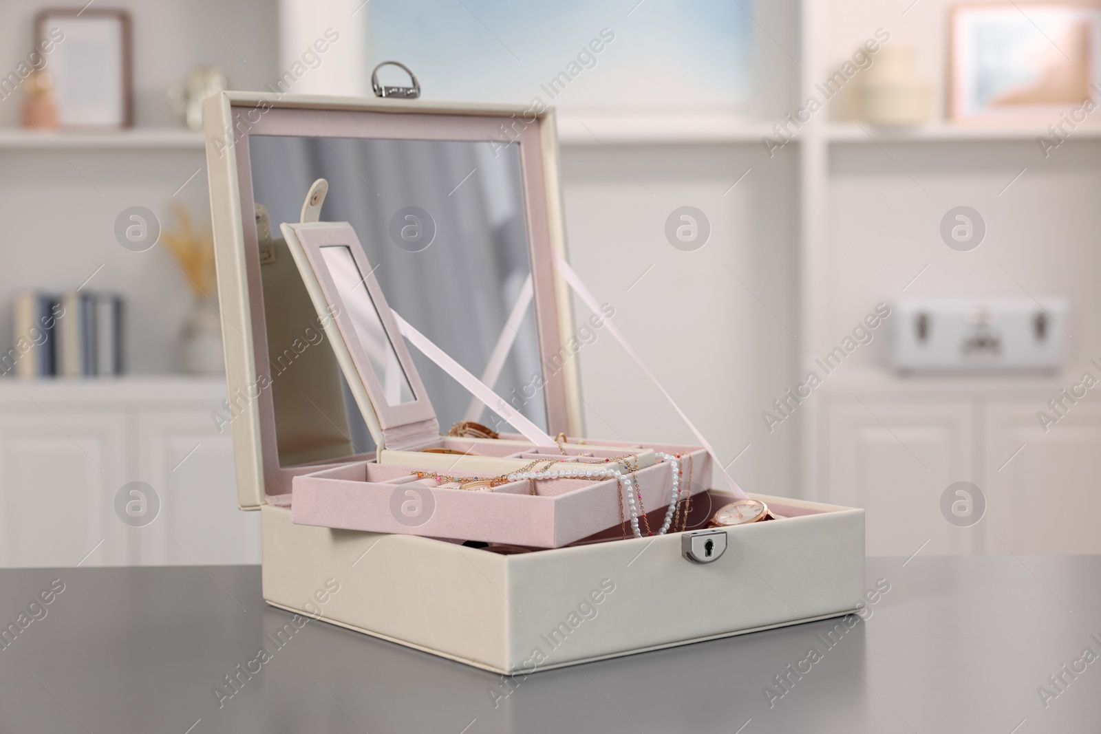 Photo of Jewelry box with mirror and many accessories on grey table indoors