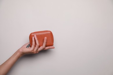 Photo of Woman holding leather purse on light background, closeup. Space for text