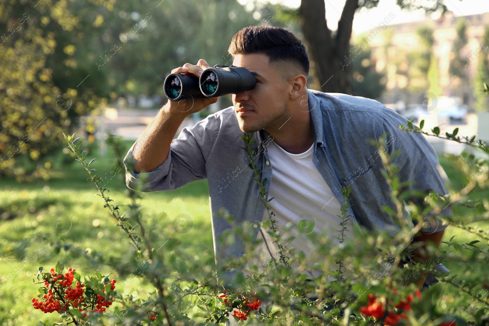 Photo of Jealous man with binoculars spying on ex girlfriend in park